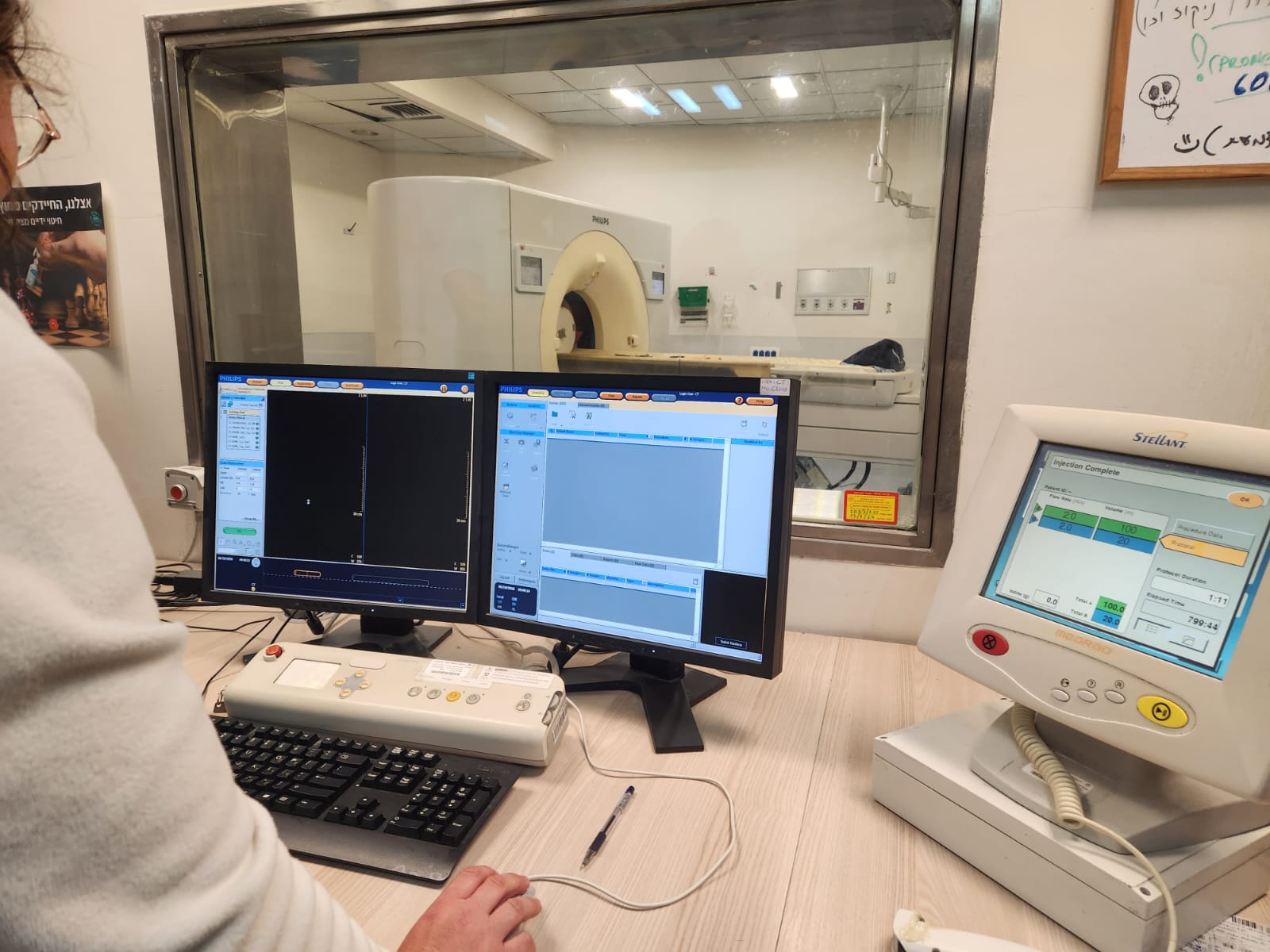 Operator at Philips Brilliance iCT 256 console with Stellant contrast injector during patient scan