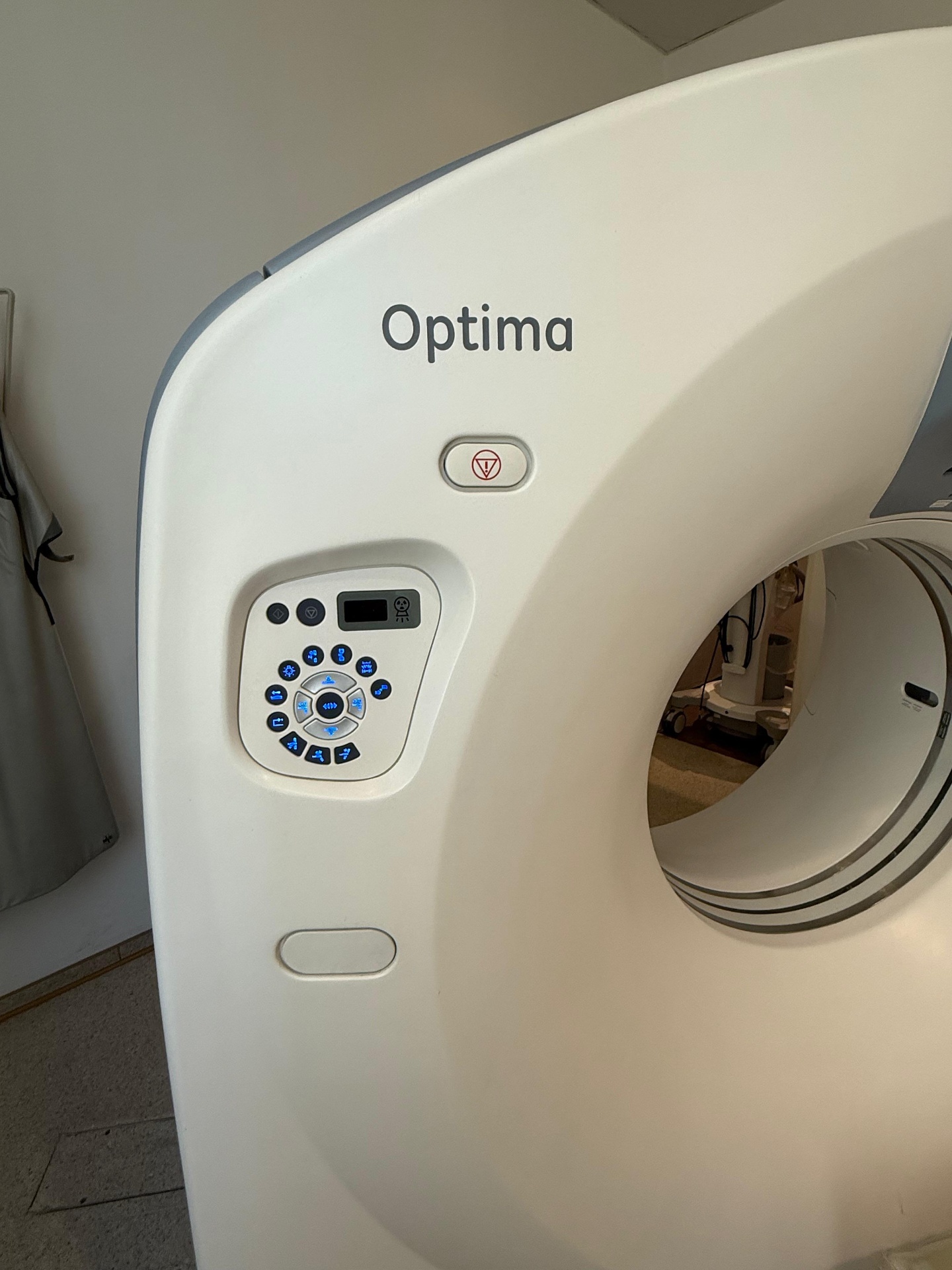 GE Optima CT520 gantry close-up showing 'Optima' branding, emergency stop and operator keypad