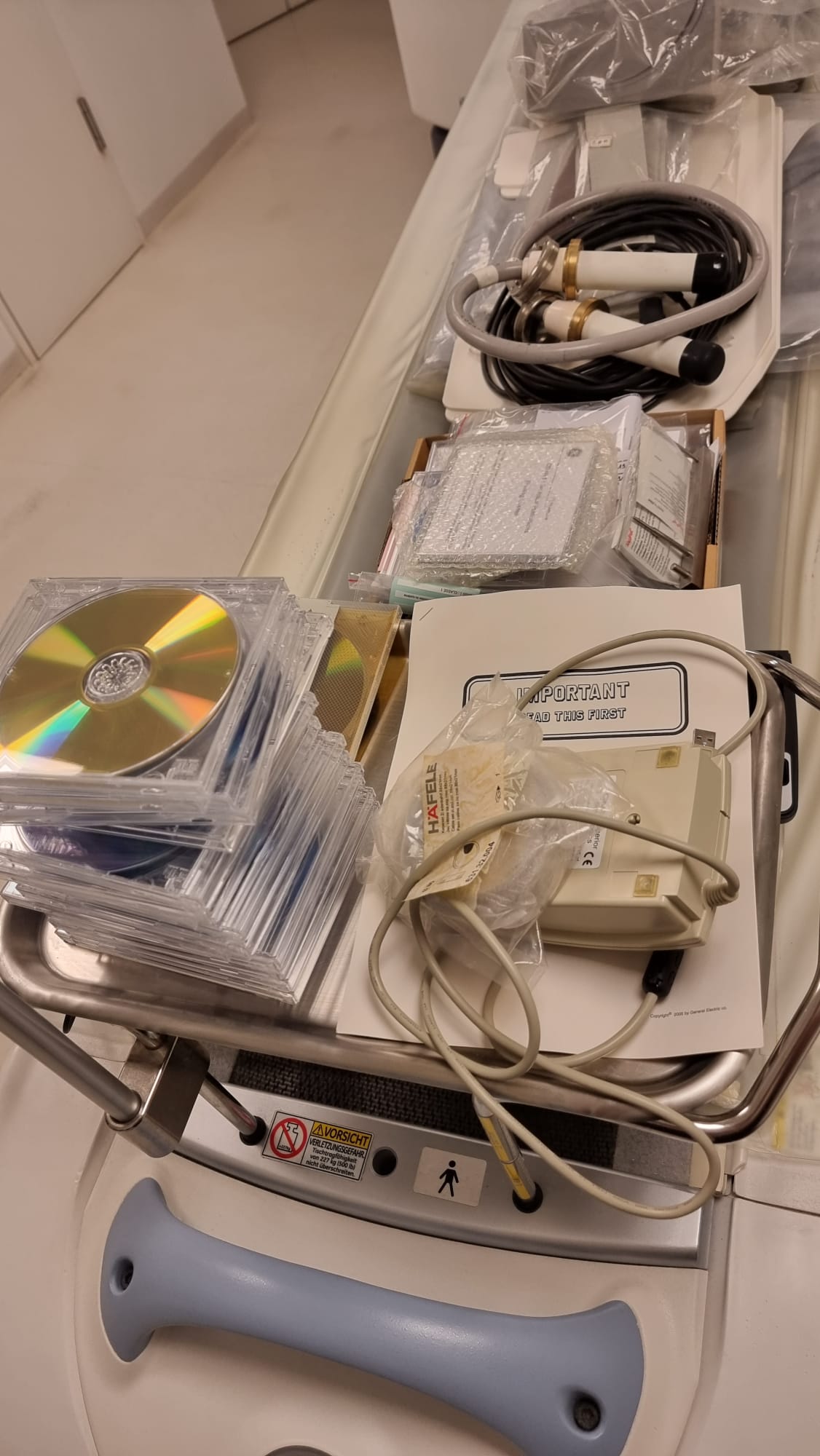 GE Optima CT660 included OEM software media, GE Locaflex high-voltage tube cables, documentation packet and system CD-ROM library staged on service cart during MTC deinstallation in Miami, Florida