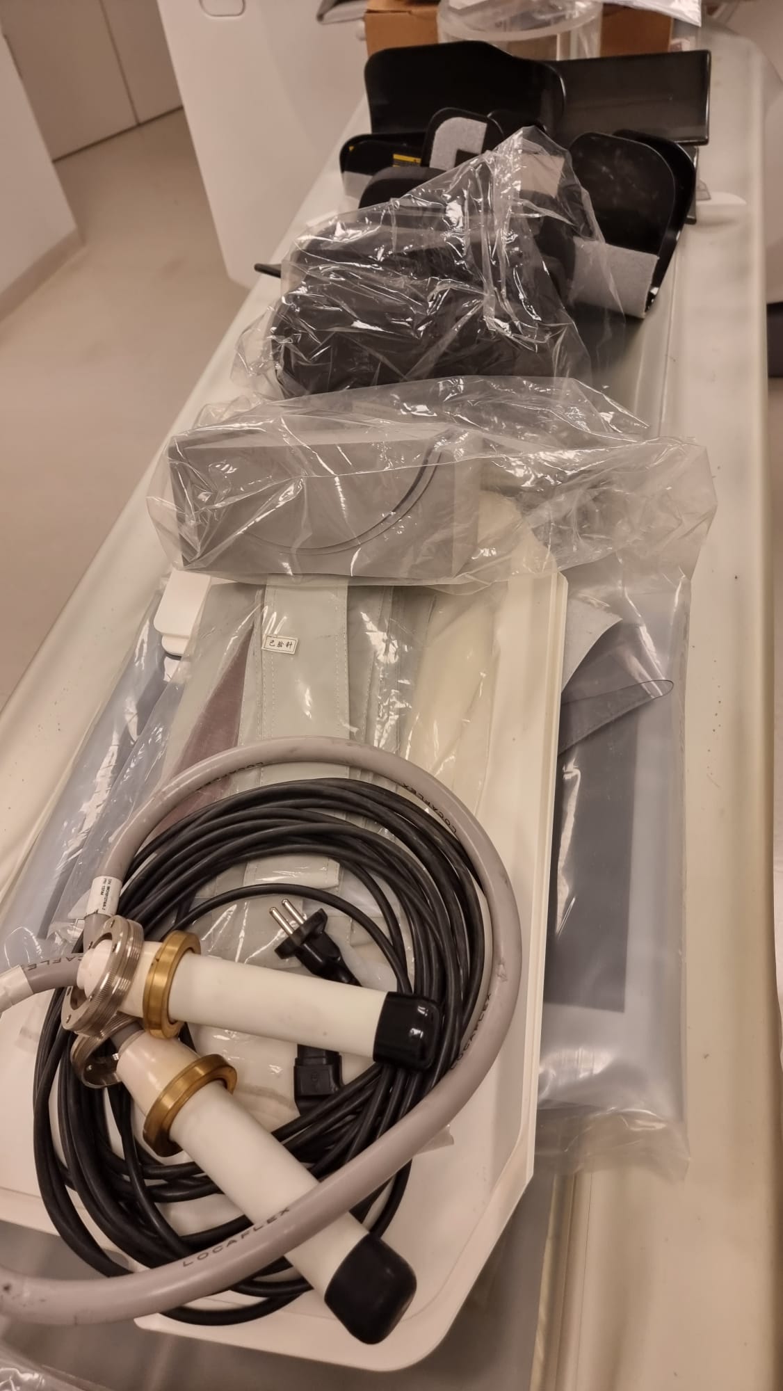 GE Optima CT660 removed PERFORMIX 40 PLUS X-ray tube assembly with high-voltage Locaflex cables and patient positioning accessories laid out on the scanner table during MTC deinstallation in Miami, Florida
