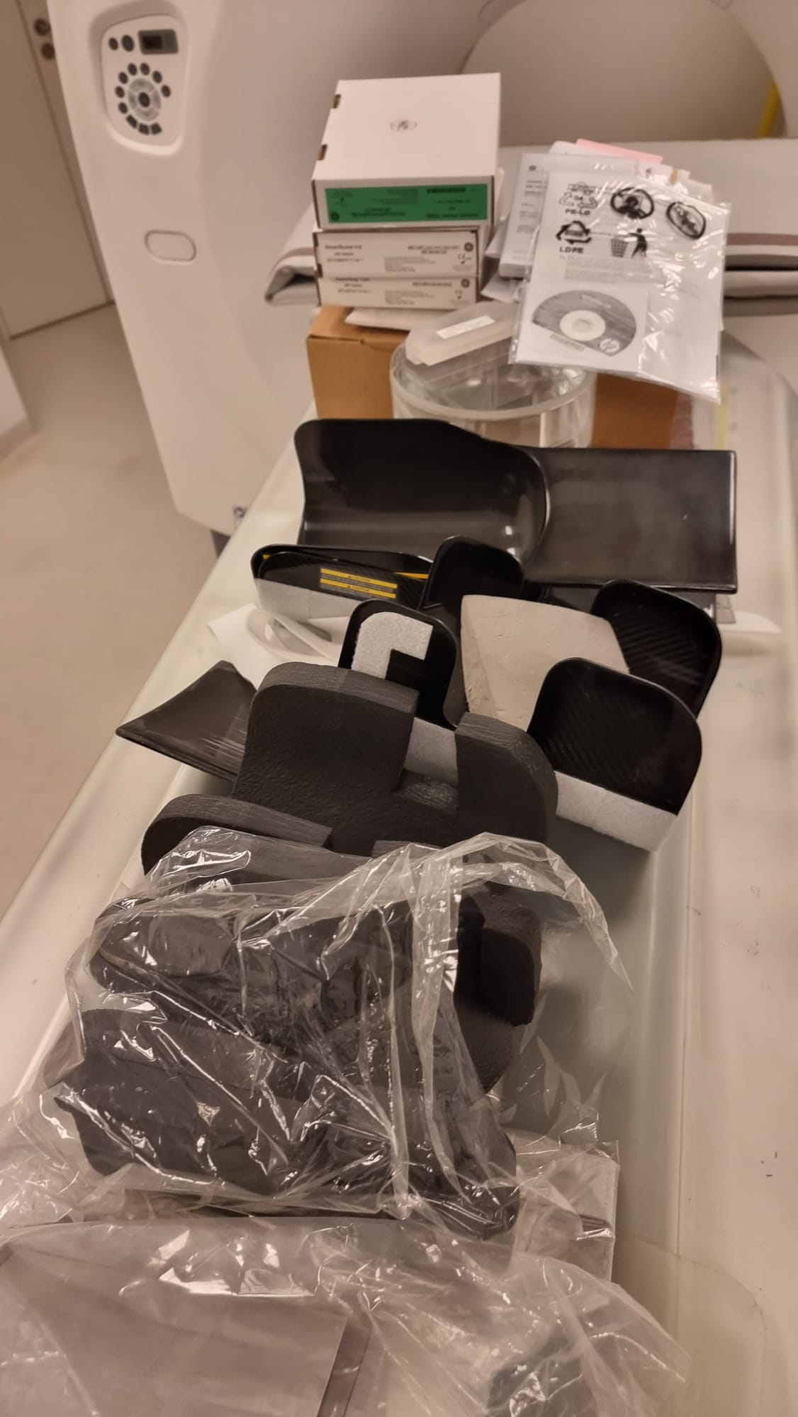 GE Optima CT660 (Optima 660) included accessory set — carbon-fiber head holders, patient positioning trays and foam cradles lined up on the scanner table during MTC deinstallation in Miami, Florida, USA